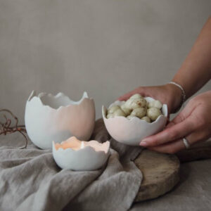Keramikskålar i form av vita ägghalvsskal. Skålen finns i tre olika storlekar hos Presenteriet.